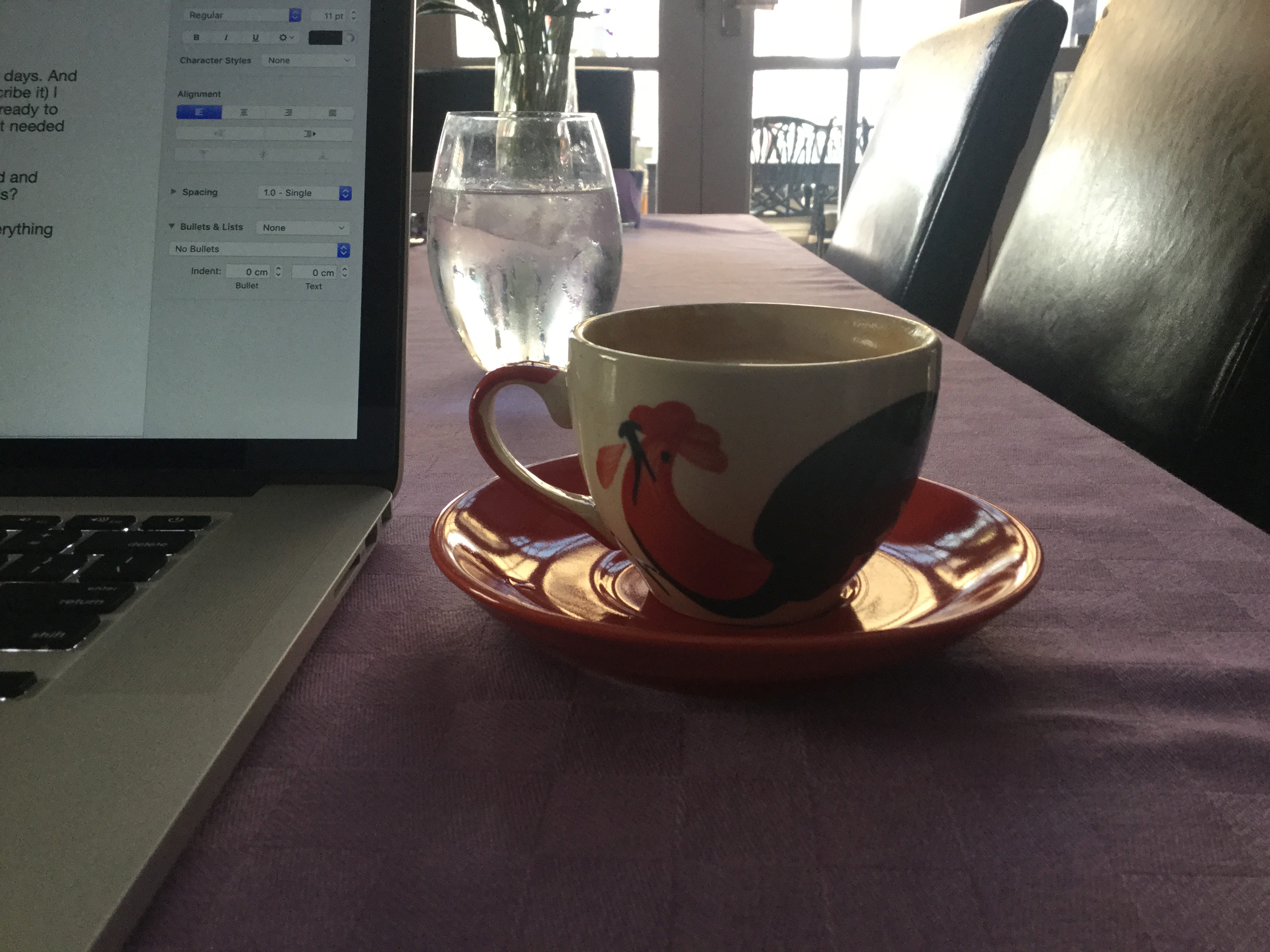 A computer screen, coffee cup and glass of water